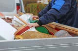 Eine Person in blauem Anzug durchsucht einen Container, der mit Sperrmüll gefüllt ist.