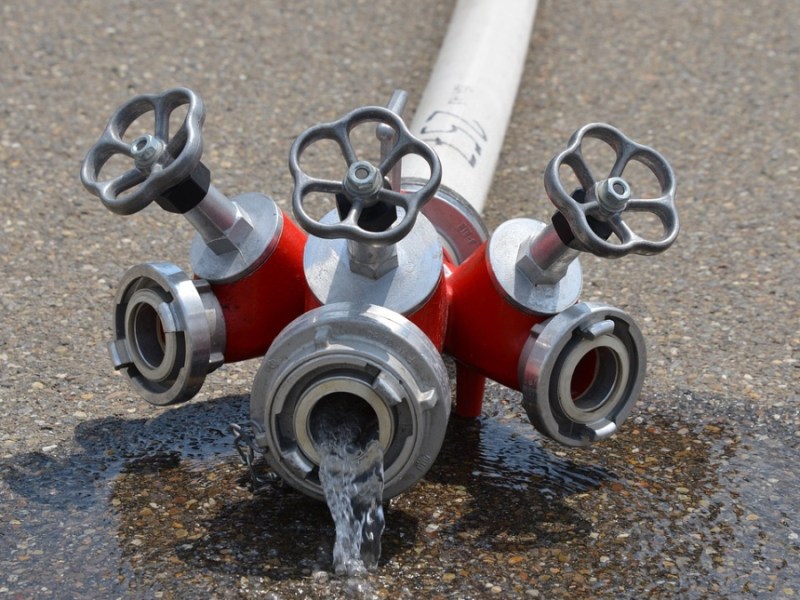 Ein Feuerwehrschlauch liegt auf der Straße und Wasser läuft heraus.