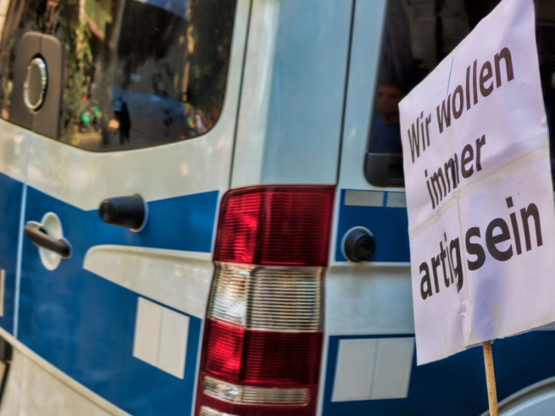 Ein Transparent an einem Stock, das vor einem Polizeiwagen steht.