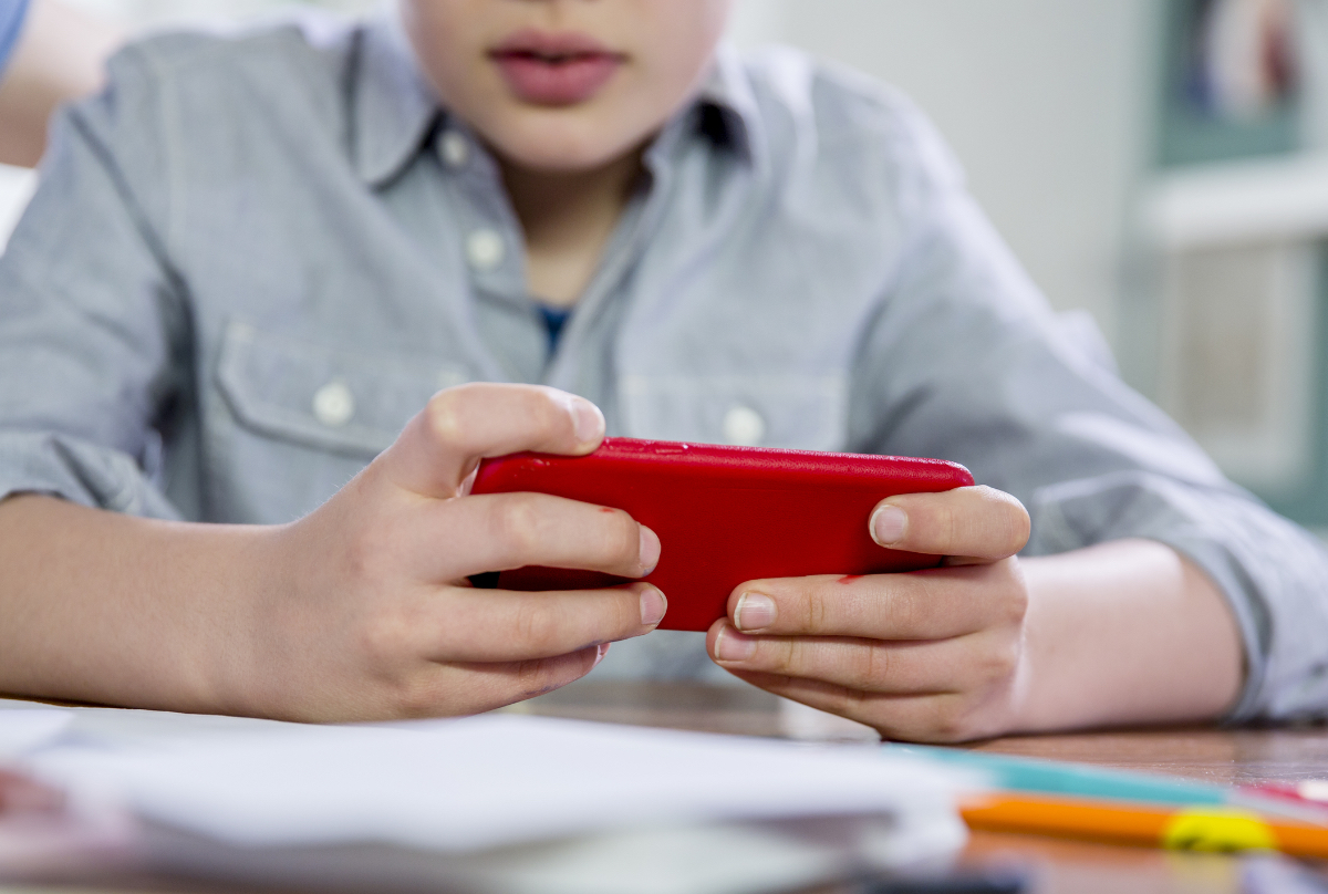 Ein blonder 10-jähriger Junge spielt Videospiele auf seinem Handy.