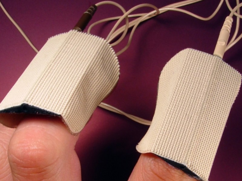 Die Finger einer Hand sind an einen Lügendetektor angeschlossen.