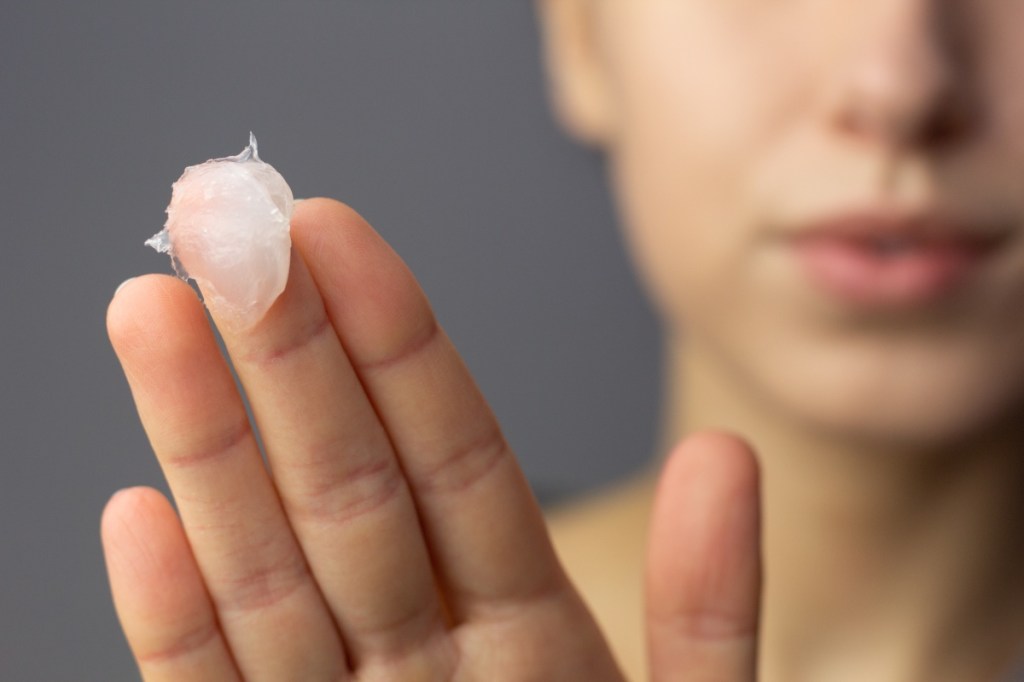 Eine junge Frau trägt Vaseline auf ihr Gesicht auf.
