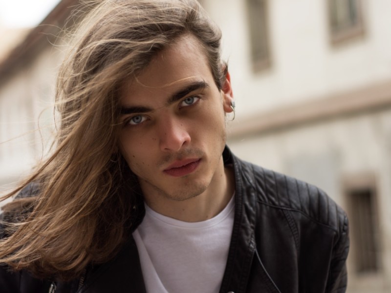 Attraktiver junger Mann mit langen Haaren und blauen Augen.