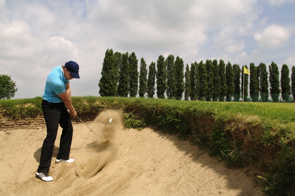 Ein Mann spielt Golf in einem Sandbunker.